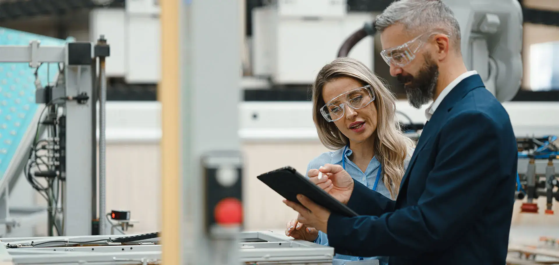 Female engineer and male production manager standing in modern industrial factory, talking about production. Manufacturing facility with robotics and automation.