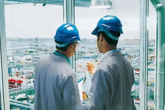 Engineers wearing hardhat having discussion in front of robotics factory